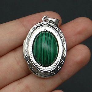Detailed view of silver oval locket with malachite stone and wave pattern engraving