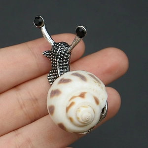 Détail d'une broche escargot avec coquille naturelle et texture en métal argenté