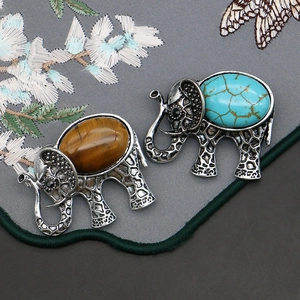 Retro elephant brooch with turquoise and tiger eye stone inlay on floral fabric
