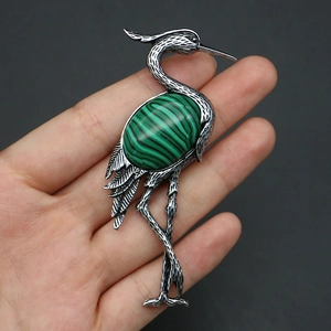 Detailed view of crane brooch with silver feather texture and green malachite stone
