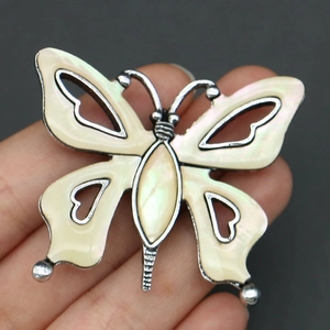 Macro detail of a butterfly brooch pendant with mother of pearl and hollowed heart patterns