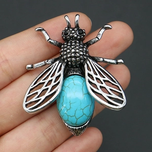 Détail macro d'une broche abeille vintage en alliage argenté et pierre turquoise ovale