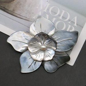 Double-layer flower brooch in natural black shell with pearl center on fashion magazine