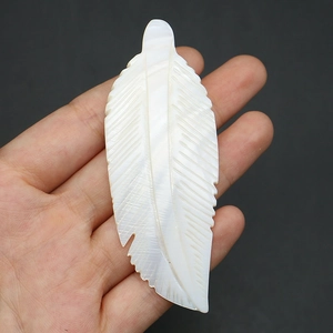 Macro shot of hand-carved white mother of pearl feather pendant with natural luster