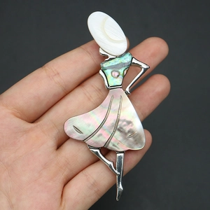 Close-up of dancing girl brooch with colorful abalone shell inlay and silver metal frame