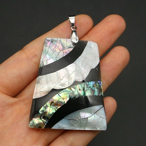 Detailed macro view of trapezoid shell mosaic pendant with iridescent abalone shell flakes