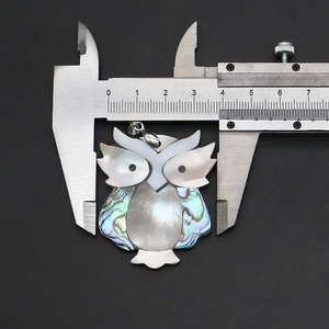 Détail macro du pendentif hibou en nacre naturelle avec une règle de mesure de 3,8 cm