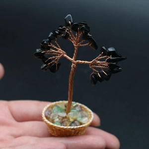 Macro shot of handcrafted mini crystal tree with black stone leaves held in palm