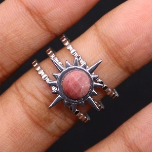 Detailed close-up of a silver sunburst ring with pink stone and triple beaded bands