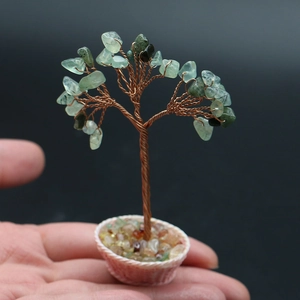 Macro view of a handmade green gemstone money tree bonsai held in a person's hand