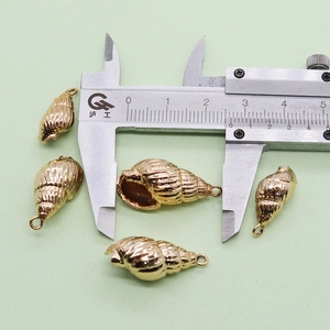 Vue macro de pendentifs coquillages dorés mesurés avec un pied à coulisse pour la dimension