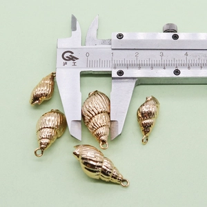 Détail macro de cinq pendentifs coquillages plaqués or avec mesure sur un pied à coulisse