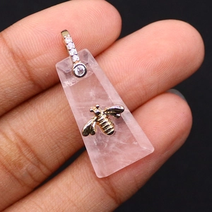 Primer plano de colgante trapecio de cuarzo rosa con abeja dorada y cierre con diamantes