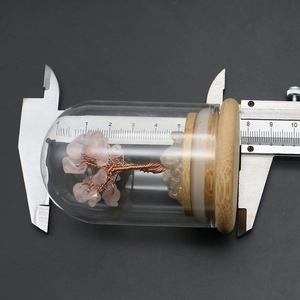 Macro shot measuring pink crystal money tree height with a digital caliper at 8cm