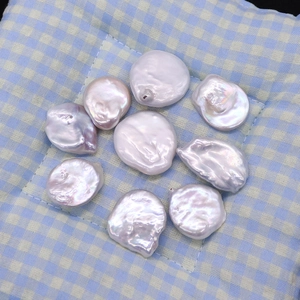 Irregular natural freshwater baroque pearls with pinkish metallic luster on fabric