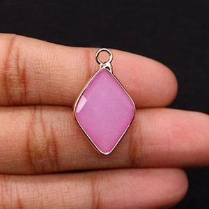 Detailansicht eines rautenförmigen rosa Steinanhängers mit Goldrand in der Hand