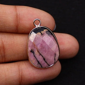 Macro shot of a teardrop-shaped natural pink rhodonite stone pendant with rose gold edging