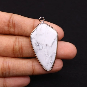 Detailed close-up of shield-shaped white turquoise pendant with gold plated edges