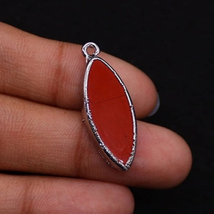 Macro shot of silver plated marquise-shaped red agate pendant held by fingers