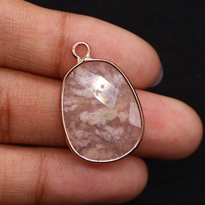 Close-up of faceted teardrop cherry agate pendant with rose gold plated metal edge