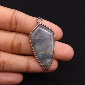 Macro detail of natural labradorite stone pendant with gold edge and colorful iridescence