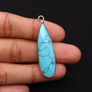 Detail of teardrop turquoise pendant with rose gold plating held by hand