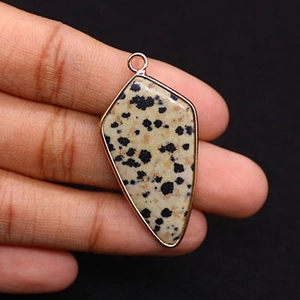 Detailed close-up of a shield-shaped Dalmatian Jasper stone pendant with gold plating