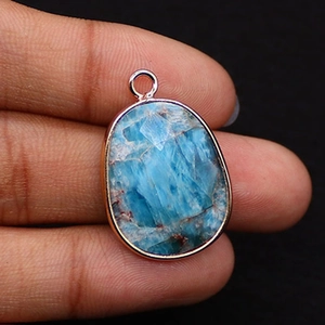 Macro shot of oval blue turquoise pendant with faceted cut and rose gold plated edge