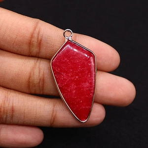 Macro detail of a red shield-shaped natural stone pendant with silver metal plating