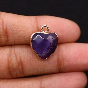 Gros plan d'un pendentif en pierre violette taillée en cœur avec bords dorés polis
