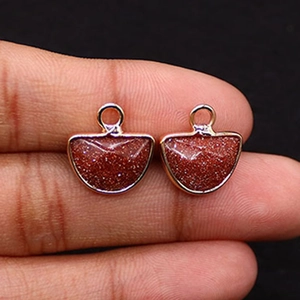 Detail of semi-circle goldstone pendants with sparkling flecks and rose gold plating