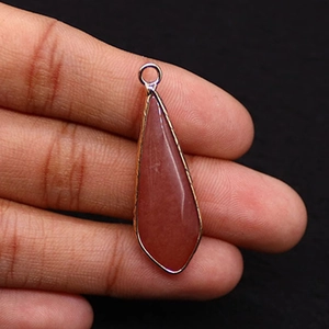 Détail d'un pendentif goutte en pierre naturelle rouge avec bordure en métal doré