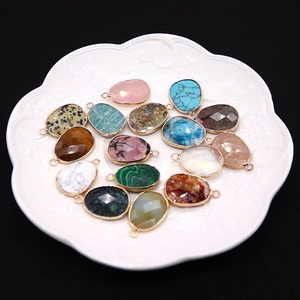 Set of 15 faceted natural stone pendants with gold plated edges in a white porcelain dish