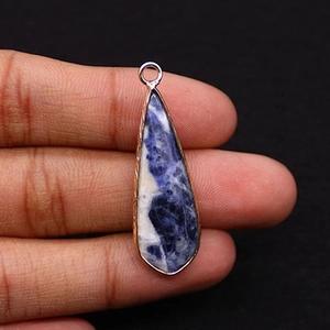 Détail d'un pendentif en pierre naturelle en forme de goutte tenu à la main pour la taille