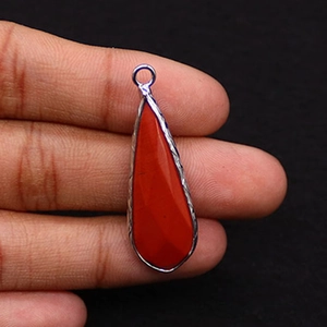 Detailed view of teardrop red jasper stone pendant held in hand for scale and size check