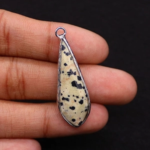 Macro shot of silver-edged teardrop Dalmatian Jasper stone pendant with black speckles
