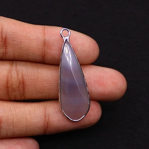 Detail of a purple teardrop natural stone pendant with silver metal frame and ring