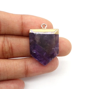 Gros plan d'un pendentif en pierre naturelle violette en forme d'épée plaqué or