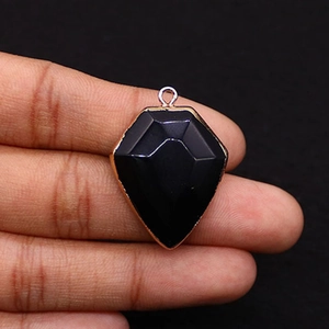 Macro view of shield-shaped black natural stone pendant with gold plated edge and hook