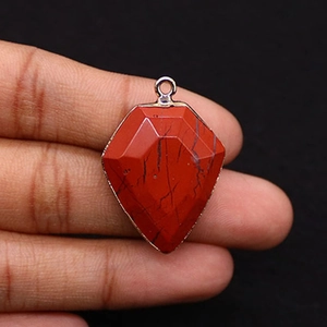 Close-up of shield-shaped red jasper stone pendant with faceted surface and silver trim