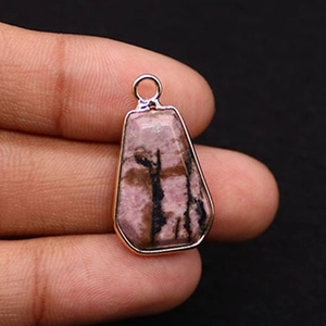 Macro shot of a trapezoid pink rhodonite stone pendant with rose gold plated metal trim