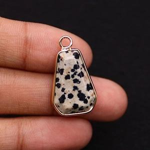 Macro detail of trapezoid dalmatian jasper stone pendant with gold plated bezel and bail