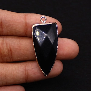 Macro view of faceted black agate arrowhead pendant with gold-plated metal edging