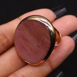 Dettaglio macro della lunetta dorata e della pietra di cristallo naturale rosa sull'anello