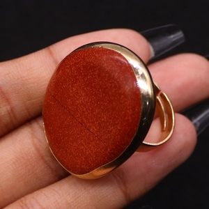 Dettaglio dell'anello regolabile placcato oro con una grande pietra naturale rossa