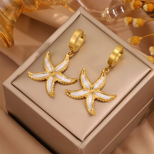 Vue détaillée de boucles d'oreilles étoile de mer en or et émail blanc sur présentoir