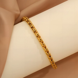 Dettaglio ravvicinato di un bracciale a catena dorata su supporto cilindrico ed elegante