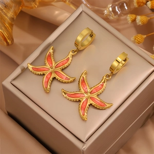 Détail de boucles d'oreilles étoile de mer avec émail orange sur base en acier doré