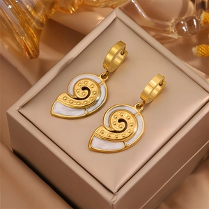Vue macro de boucles d'oreilles coquillage doré avec émail perlé blanc et points d'or