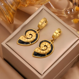 Détail de boucles d'oreilles coquillage dorées avec émail noir sur écrin à bijoux de luxe